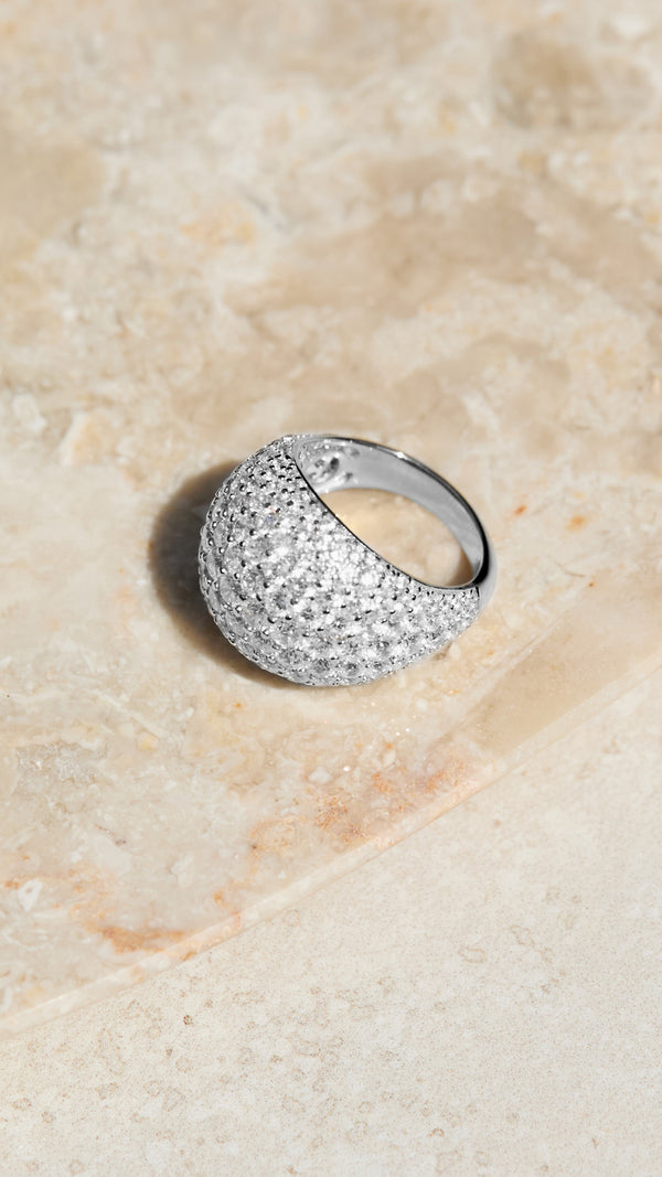 Sterling silver dome ring with gemstone accents on a beige stone surface