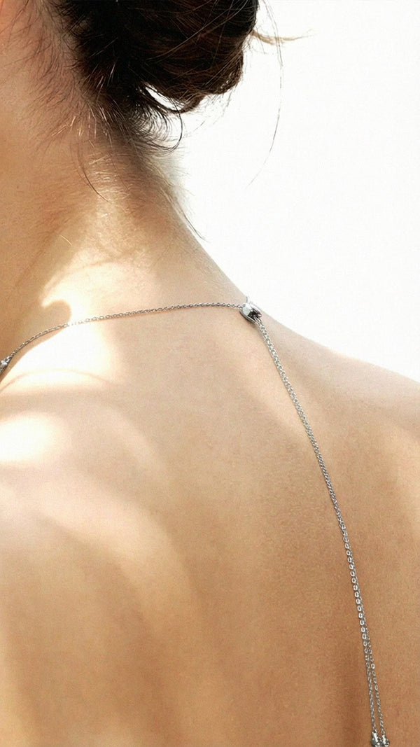 Close-up of a necklace on a person's neck with a necklace down the back blurred background