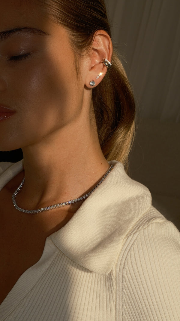A sterling silver ear stack with layered ear cuffs paired with a diamond style tennis necklace. 