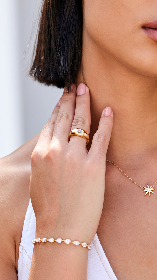 Close-up of a person wearing gold signet ring with a marquise diamond style gemstone