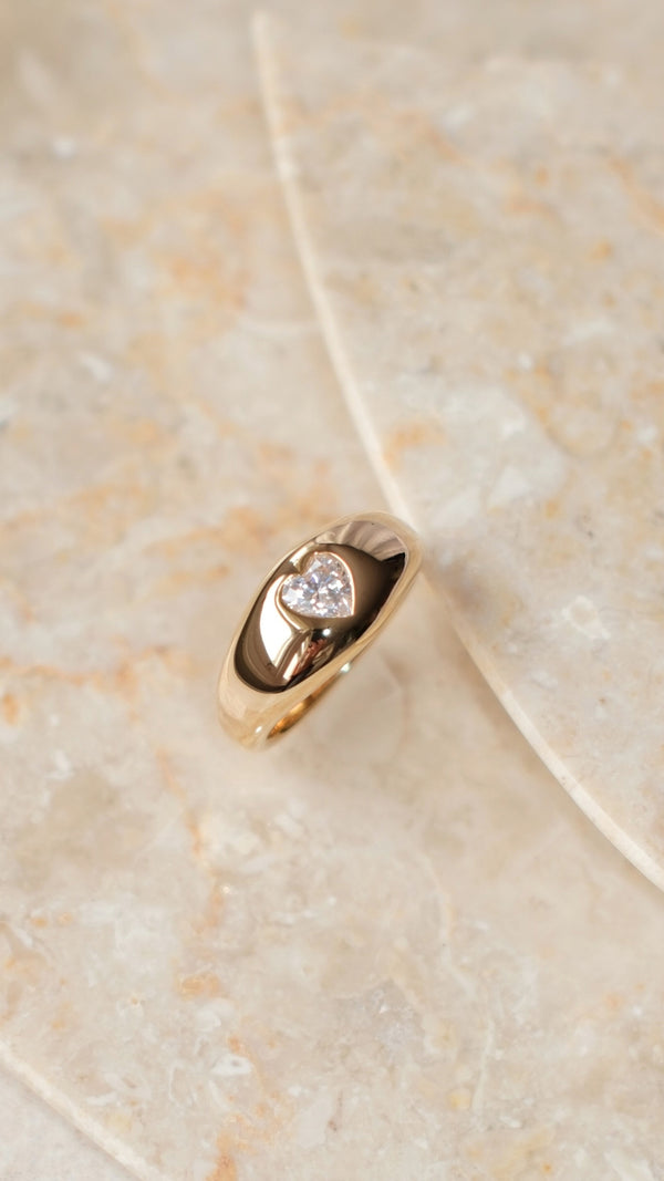 Sleek gold signet ring with a smooth polished band and heart gemstone in a bezel setting.