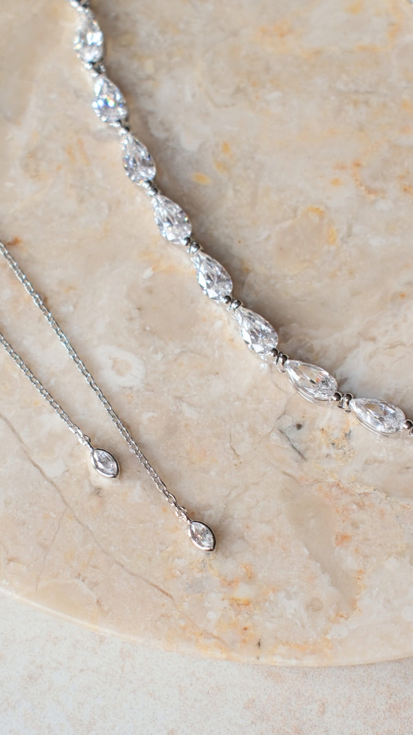 Close-up of delicate sterling silver tassels ending in bezel-set marquise stones on a slider necklace