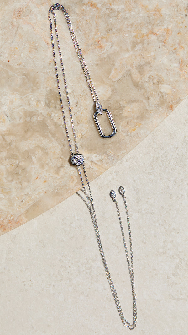 Adjustable sterling silver necklace with a marquise pendant on a beige stone surface