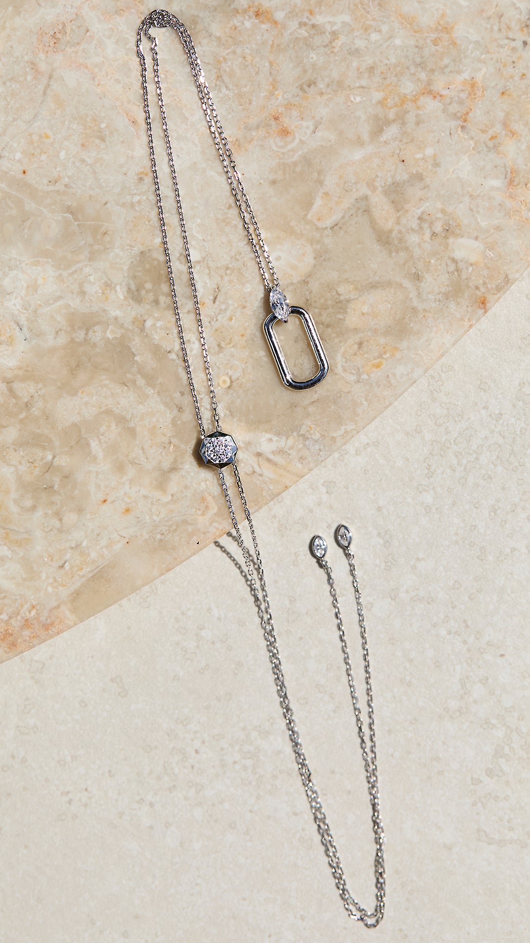 Adjustable sterling silver necklace with a marquise pendant on a beige stone surface