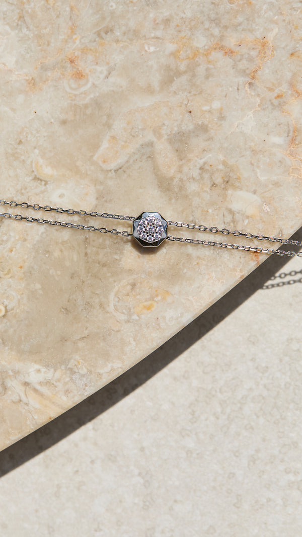 Silver necklace with a decorative adjustable slider on a beige stone surface