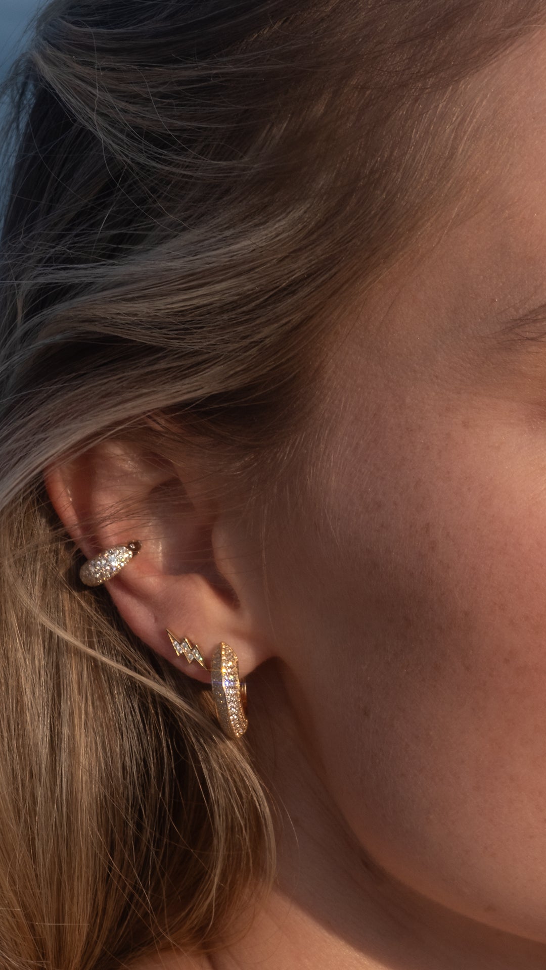 Gold hoop earrings paired with lightning stud earring and gold ear cuff earrings for women